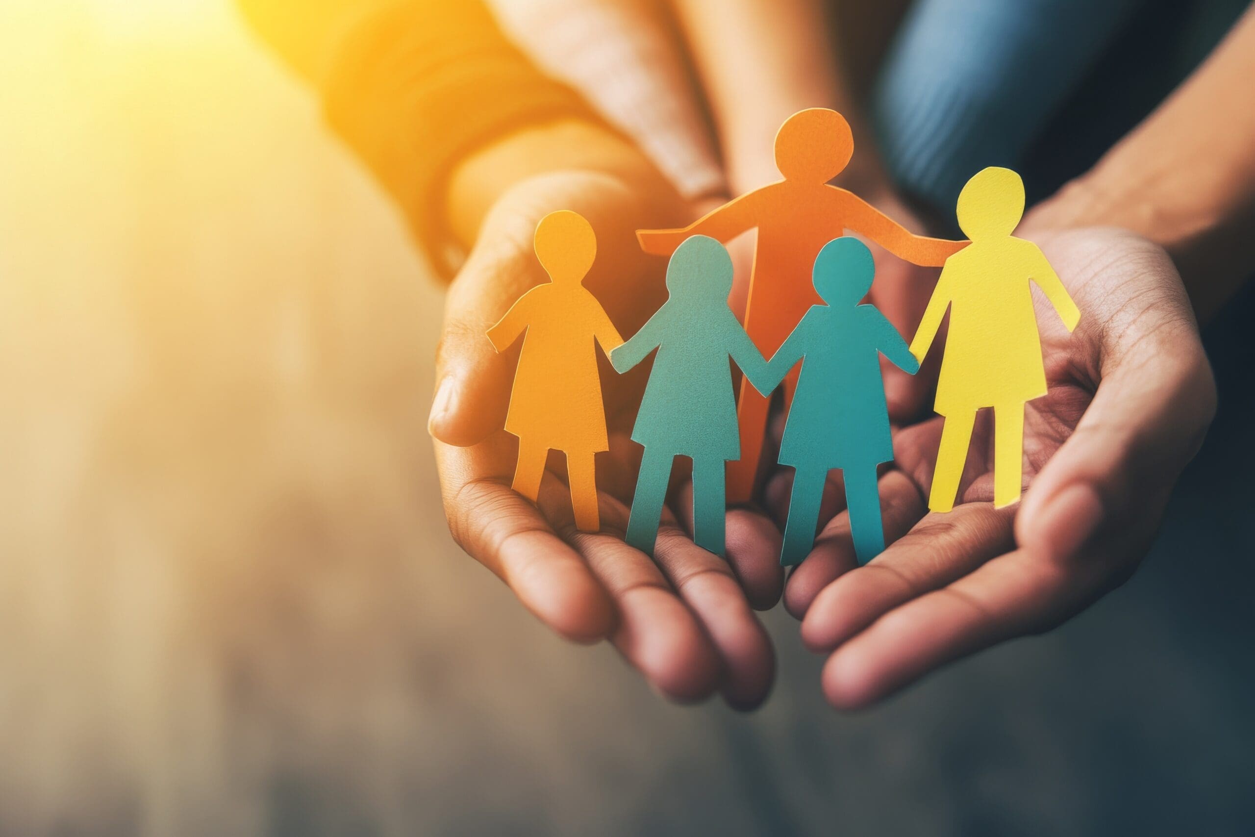 Hands holding paper figures representing family support, housing stability, and community care services.