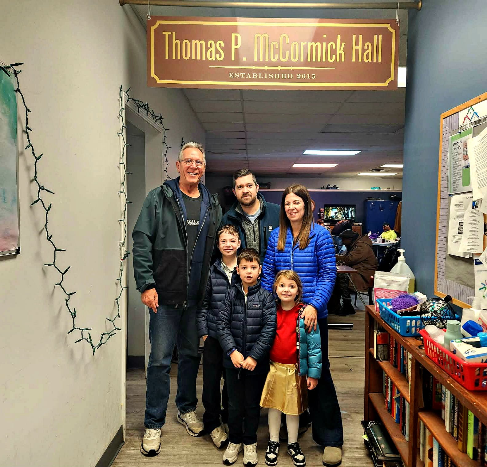 Family standing with community leaders inside Thomas P. McCormick Hall, a transitional housing and support facility for families in Michigan City.