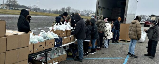Residents receive groceries and fresh food through a community food distribution program supported by local volunteers.
